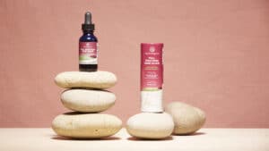 Ojai Energetics Full Spectrum Hemp Elixir bottle with stones and a pink background