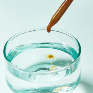Dropper adding CBD oil into a glass of water to demonstrate water soluble CBD