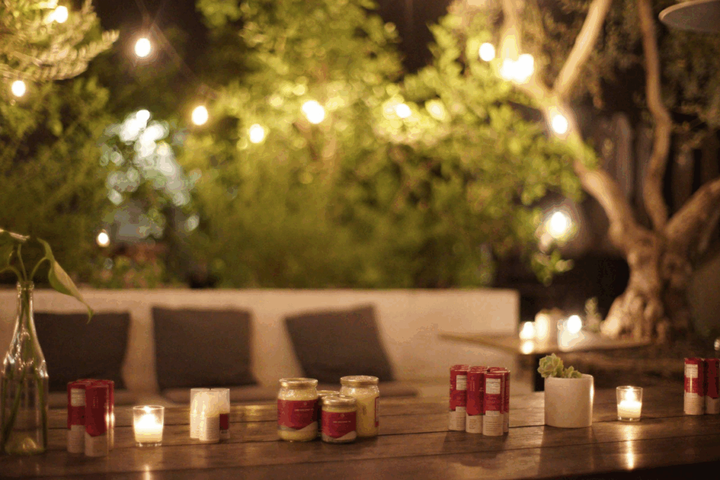 Ojai Energetics CBD products displayed on a wooden table with candles and string lights in a cozy outdoor setting