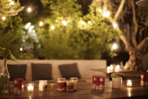 Ojai Energetics CBD products displayed on a wooden table with candles and string lights in a cozy outdoor setting